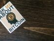 Ask me about Bitcoin flyer on top of a wooden surface